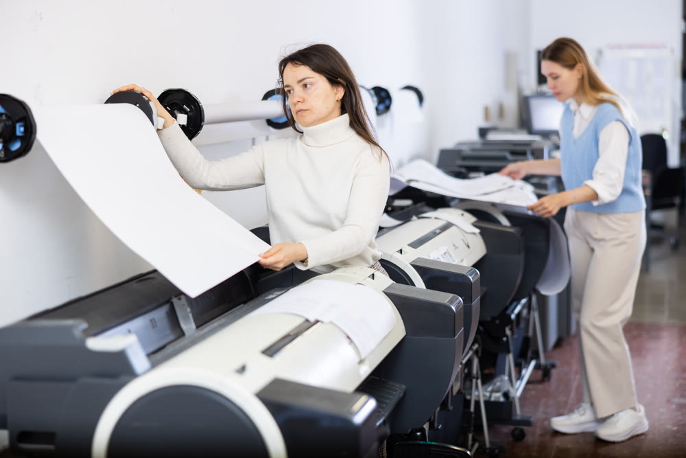 Print worker controlling printing process on modern offset machine in print shop