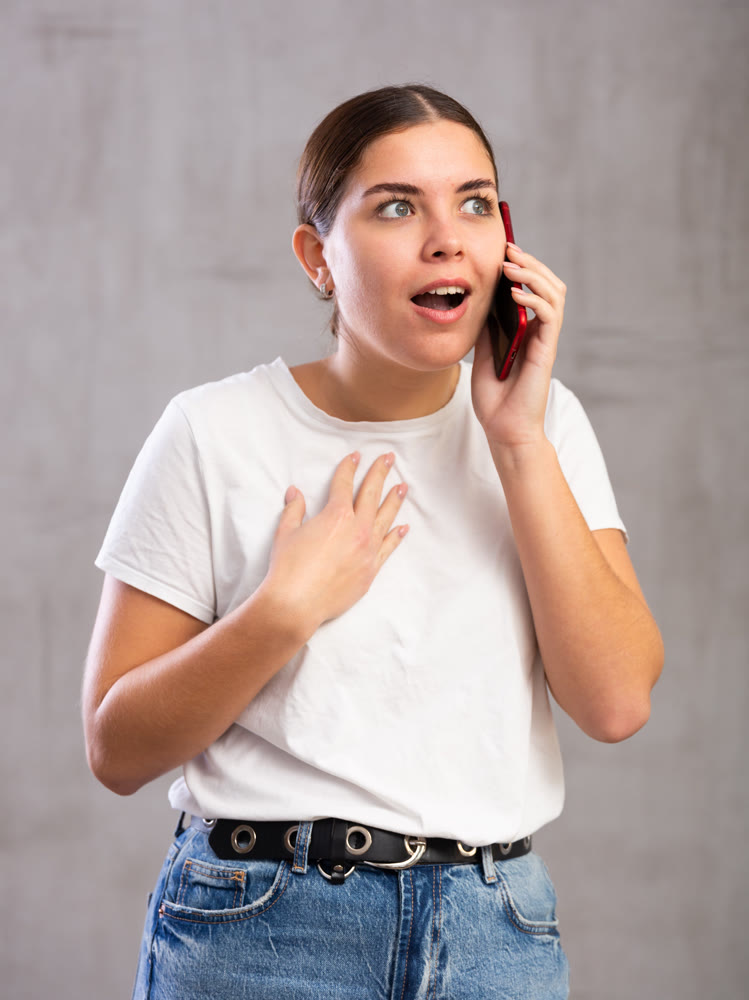 Surprised young woman talking on mobile phone