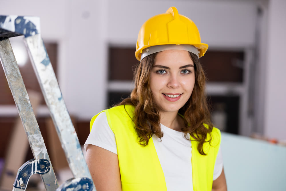 Portrait of young woman builder standing in apartment