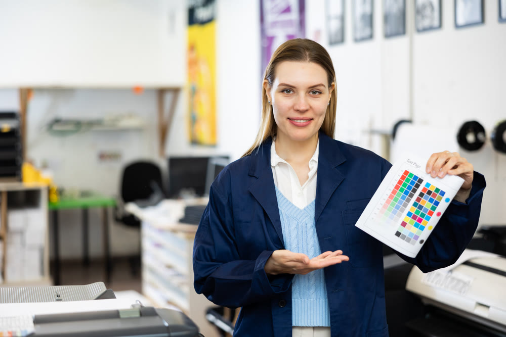Positive woman publishing facility worker with colour test page