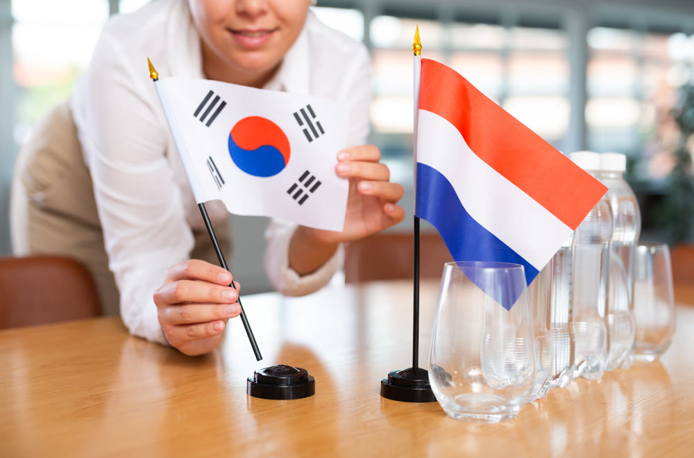 Businesswoman arranging the flags of South Korea and Netherlands for presentation and negotiations