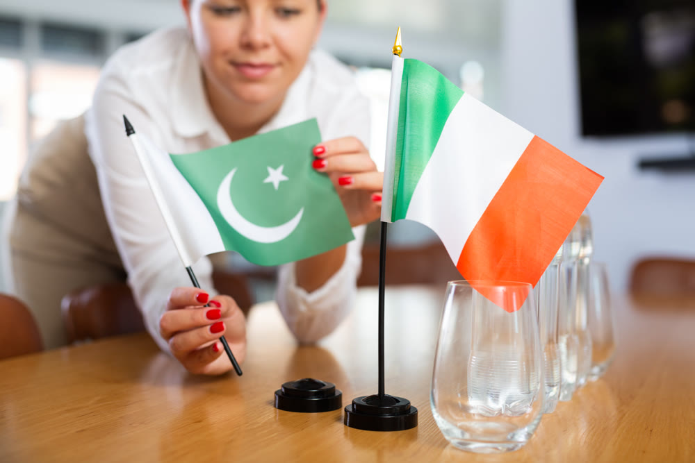 Businesswoman arranging the flags of Pakistan and Italy for presentation and negotiations