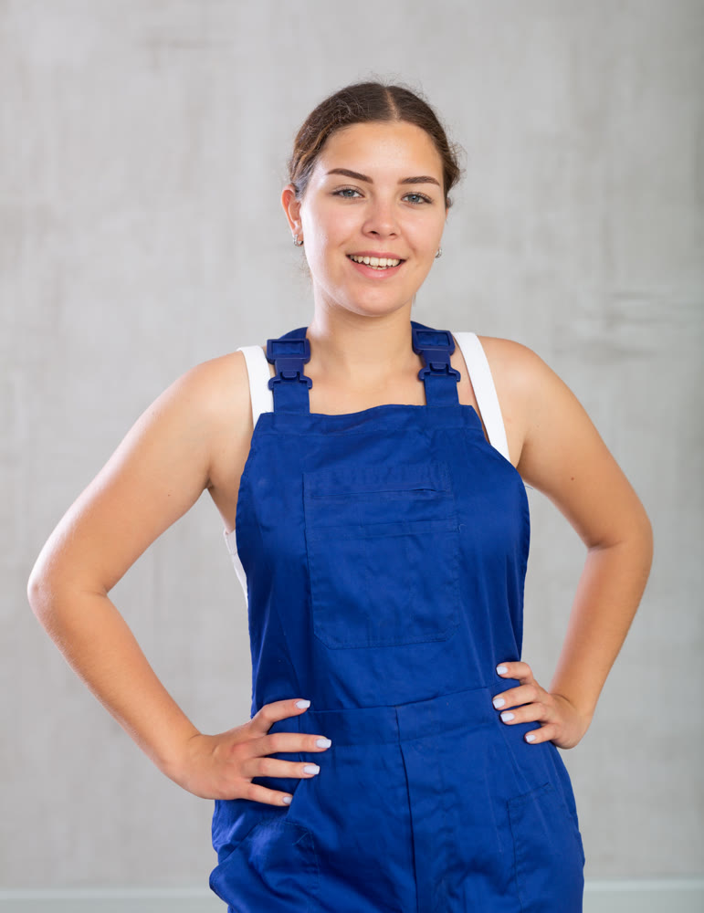 Young woman posing in work overalls in studio