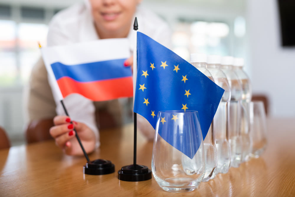 Young woman puts flags of Russia and the EU on table in office