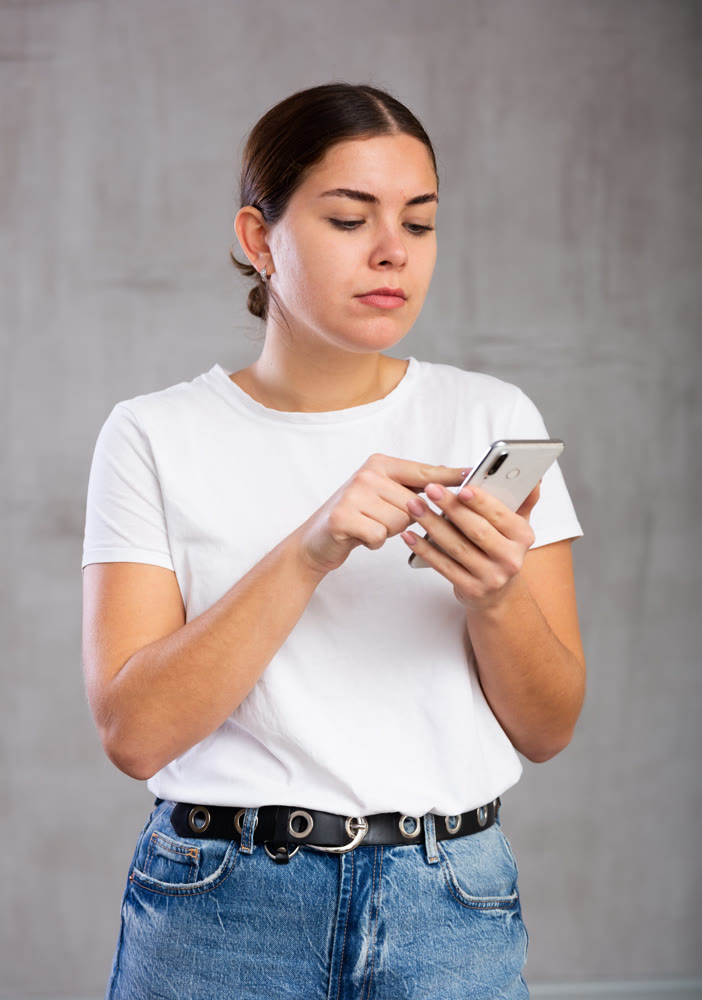 Calm young woman looking interestedly at mobile