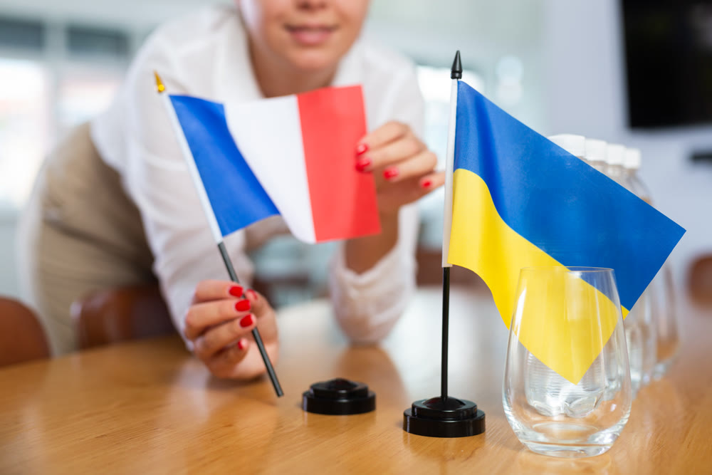 Unrecognizable girl sets midget flags of Ukraine and France before international negotiations