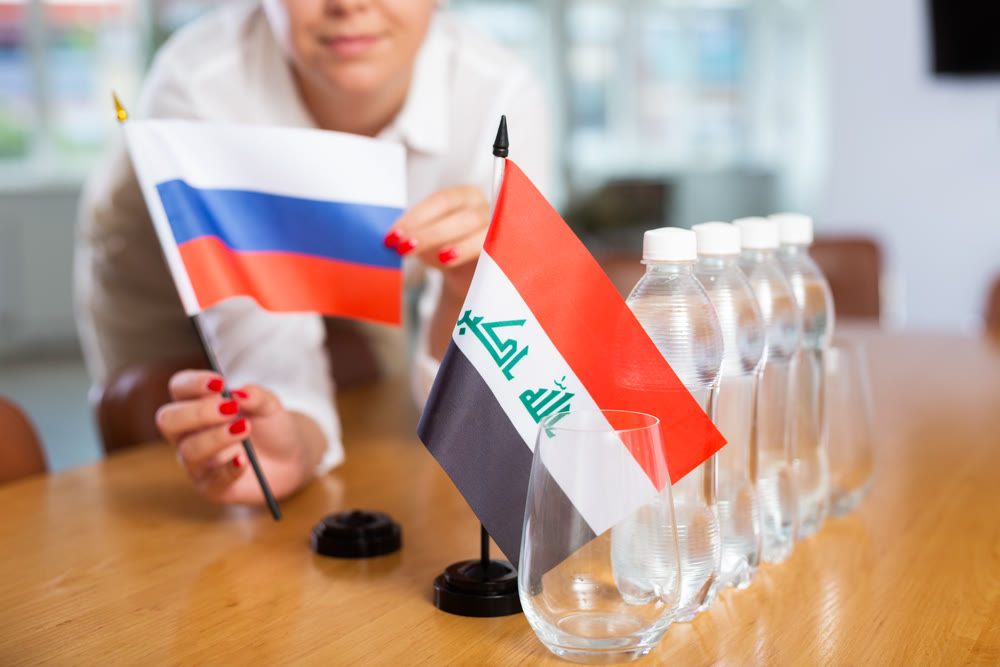 Unrecognizable girl sets midget flags of Iraq and Russia before international negotiations