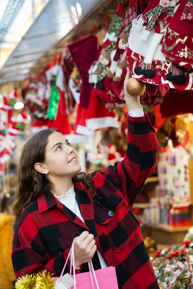 Smiling girl choosing decorations on street Christmas fair
