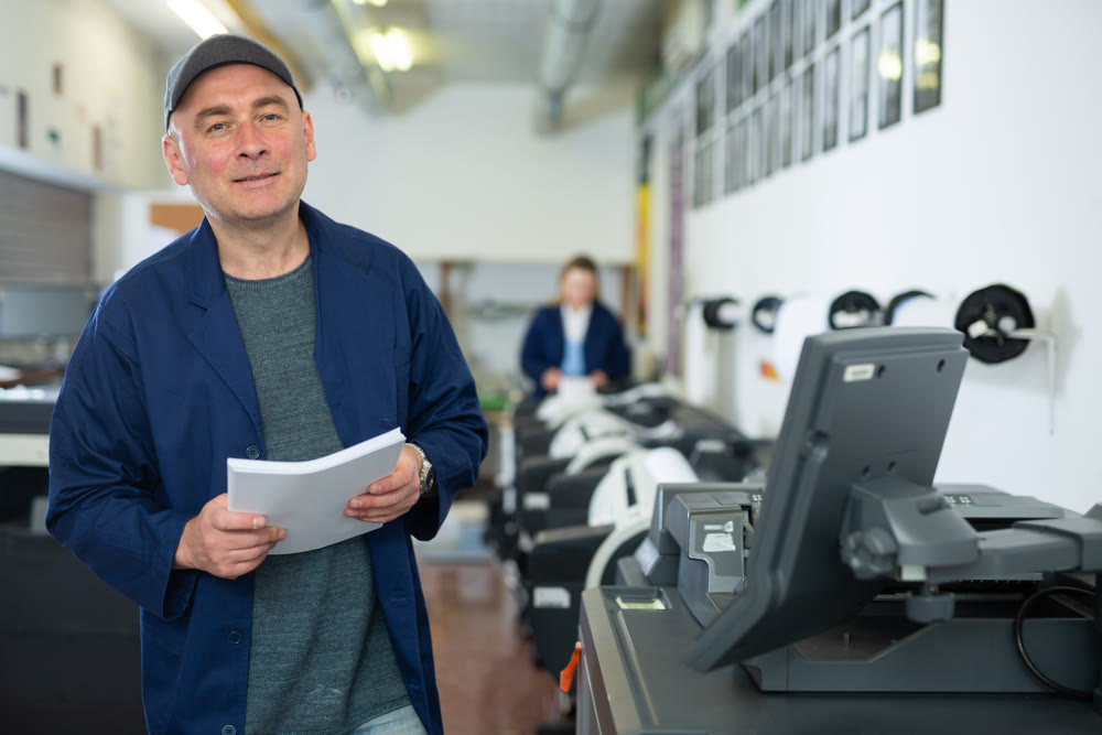 Portrait of an employee of printing house with stack of paper in his hands