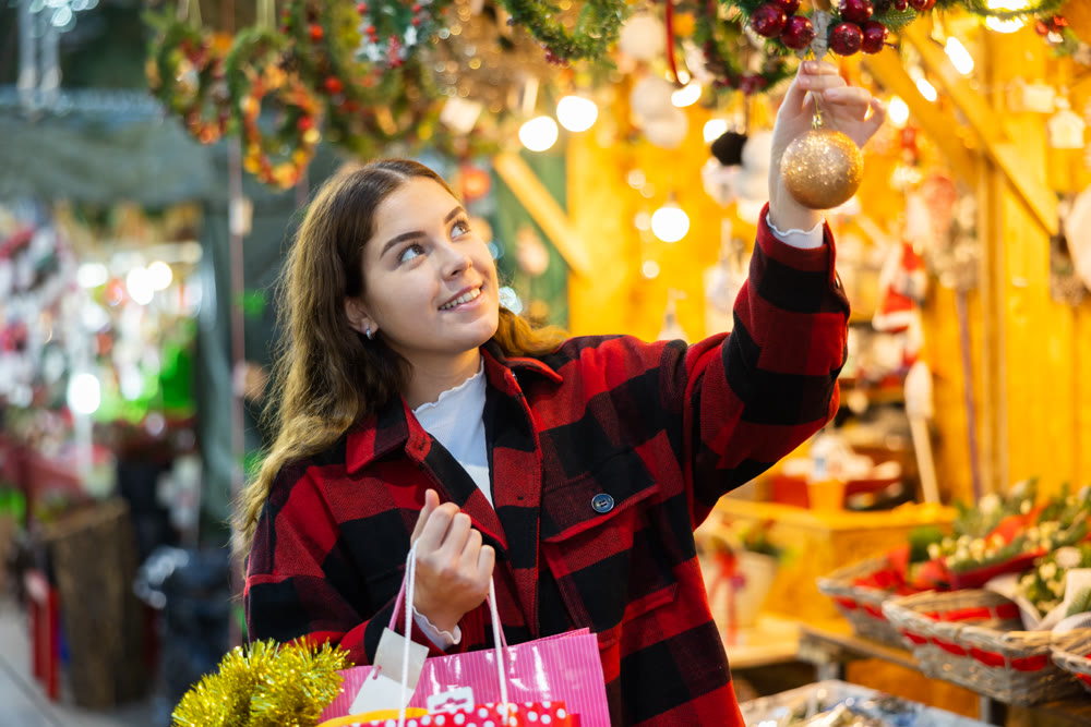 Cheerful girl viewing ball while walking at Christmas fair