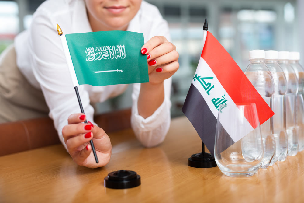 Unrecognizable girl sets midget flags of Iraq and Saudi Arabia before international negotiations