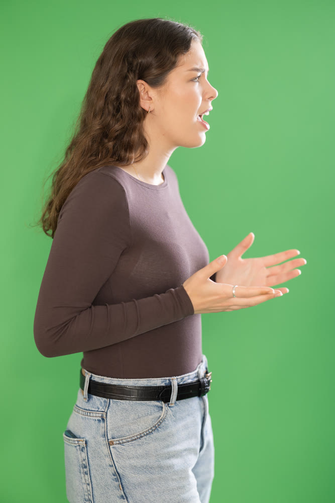 Young woman angry and yelling in front of green screen