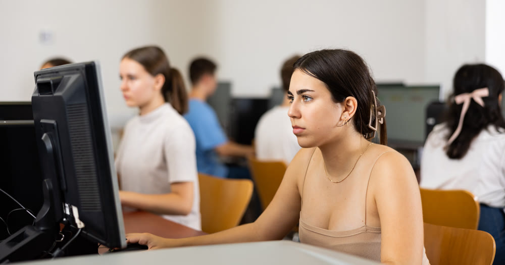 Interested teen girl studying with classmates in school class