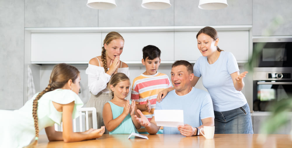 Joyful father of family with children and wife read letter in kitchen.