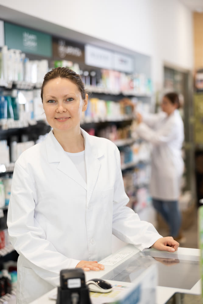 Portrait of female pharmacist at cash register in interior of pharmacy