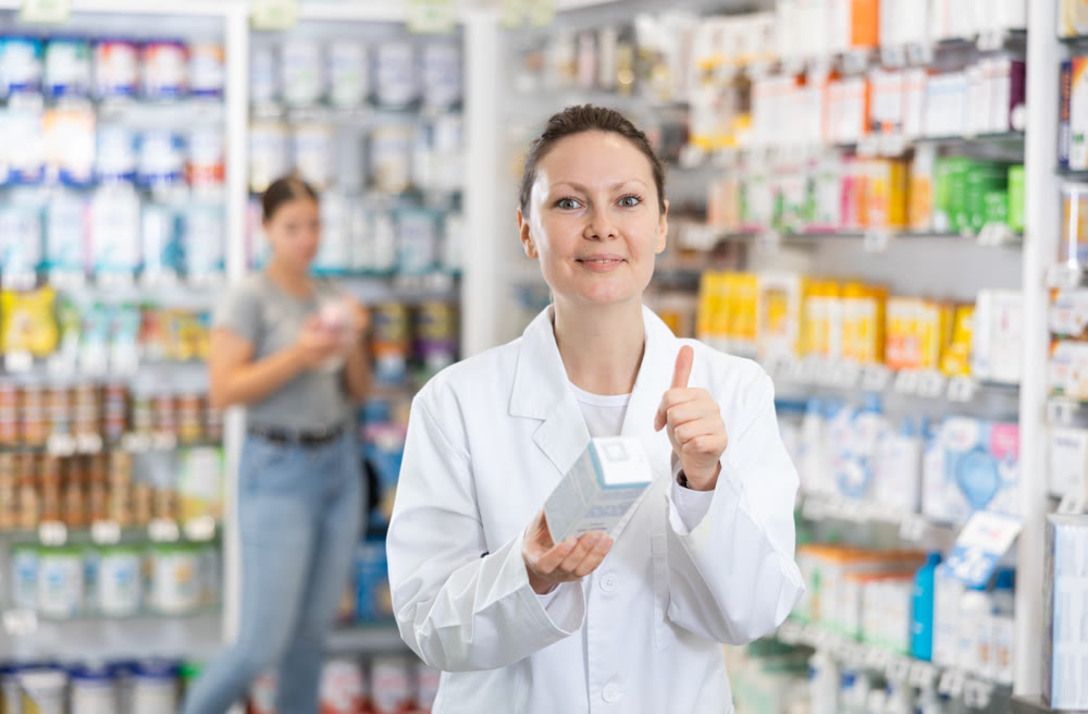 Adult female pharmacist posing with remedy in pharmacy