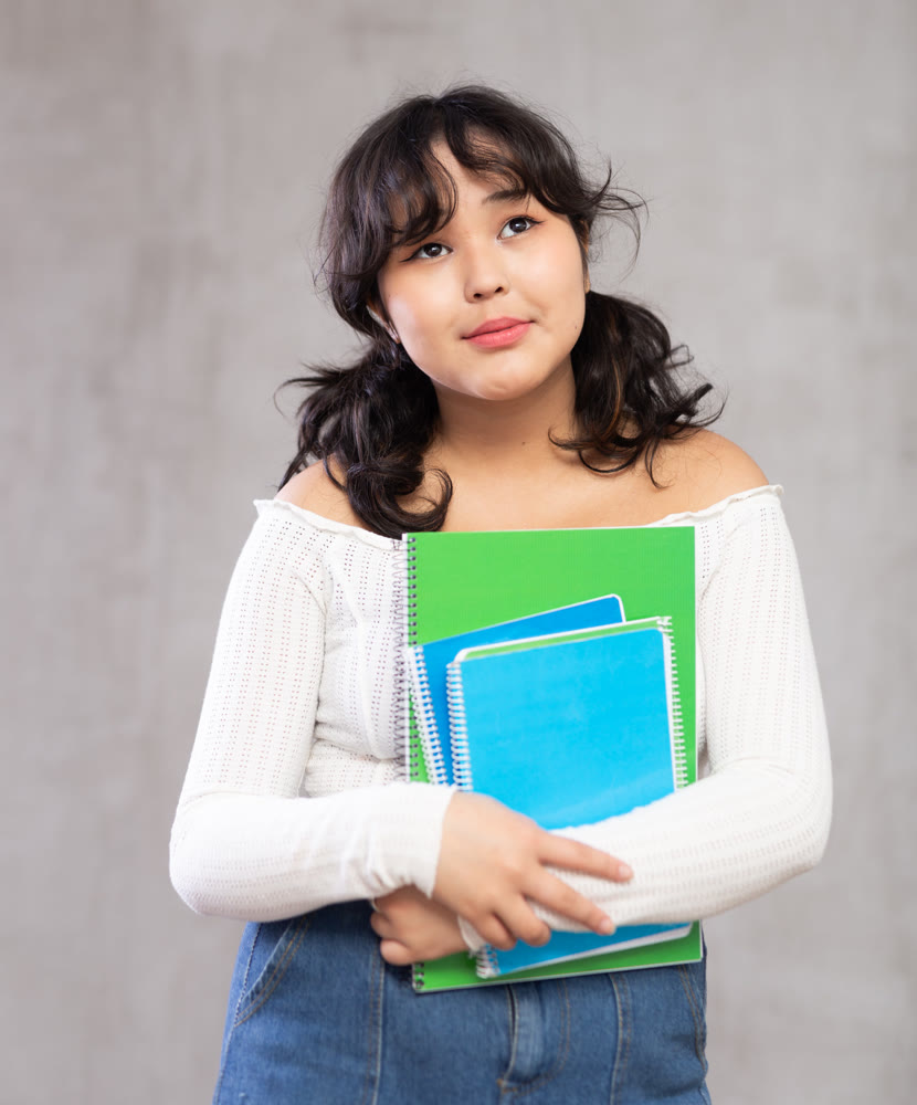 Smiling young girl with notebooks posing in studio