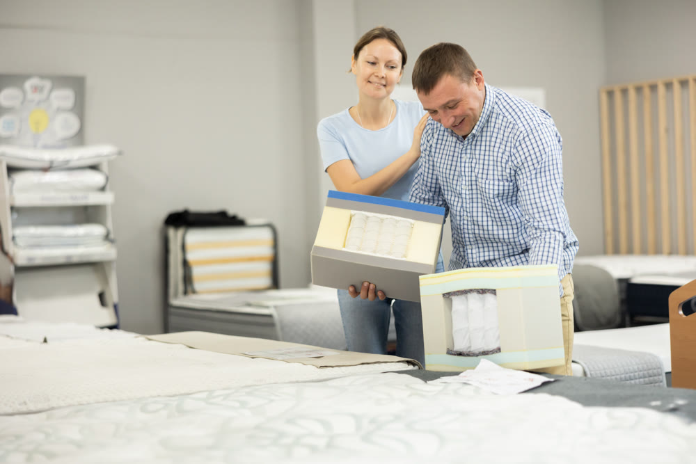 Married couple chooses and discusses mattress filling in furniture store