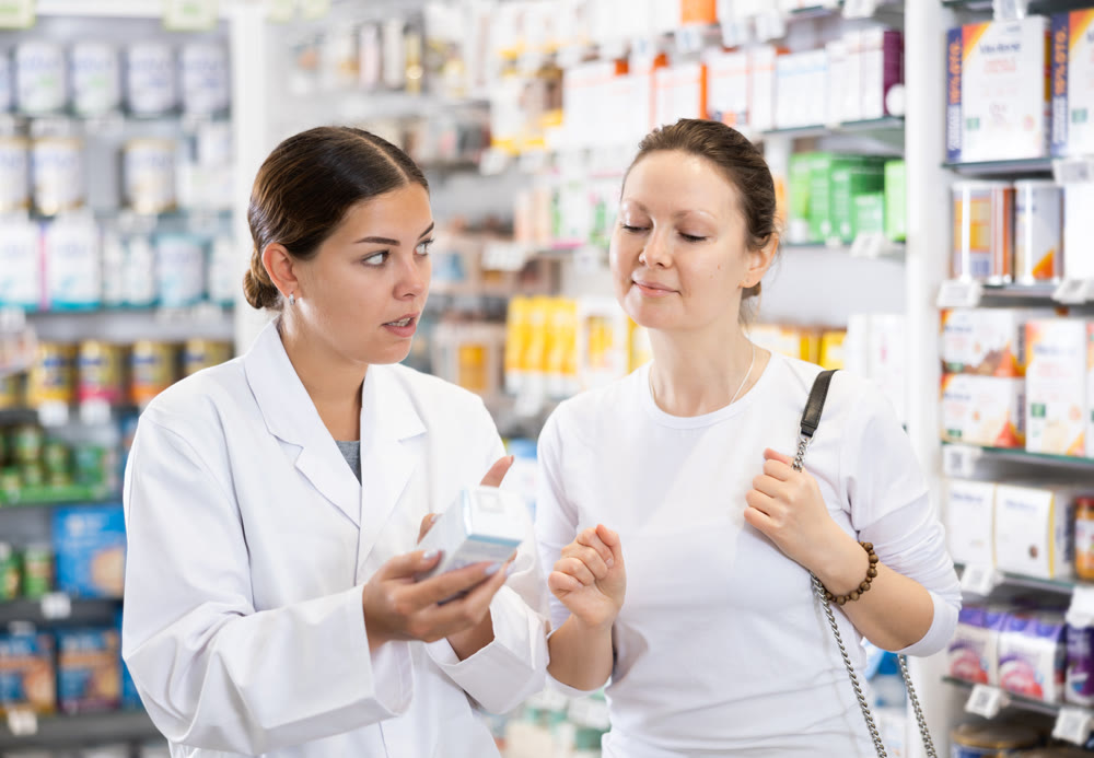 Woman pharmacist helping woman customer to choose remedy in pharmacy