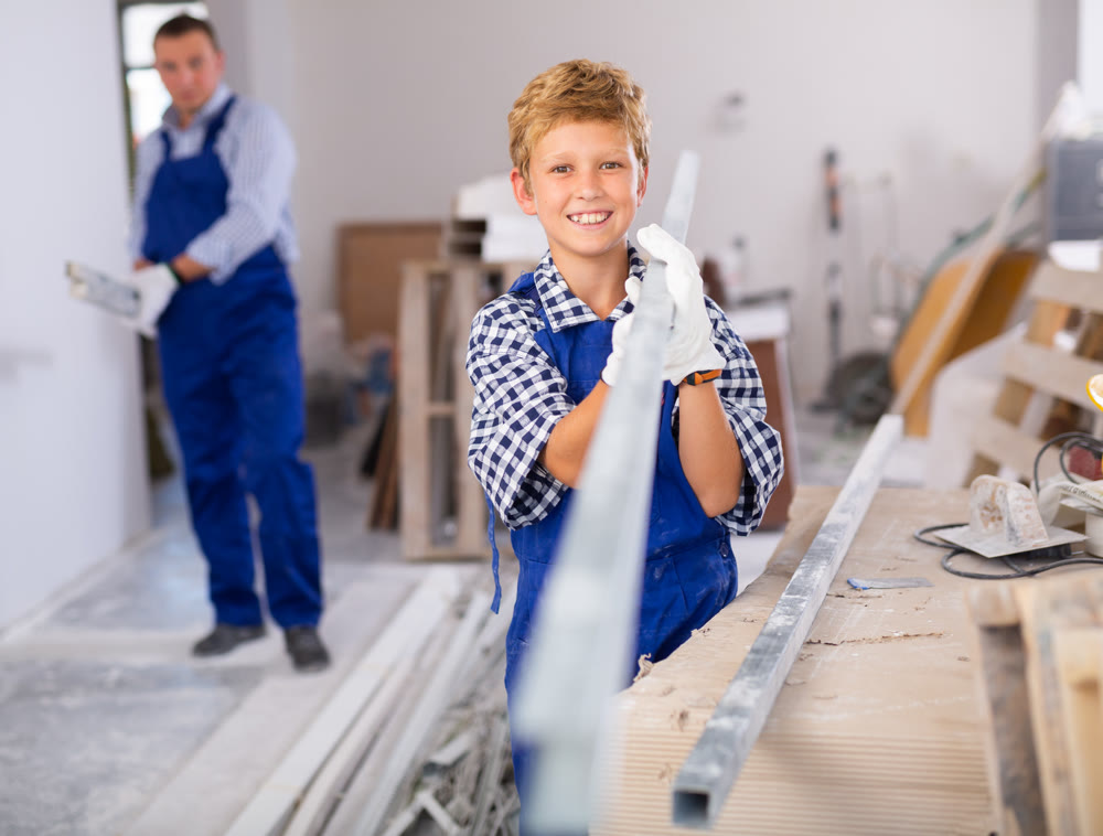 Preteen boy with father carrying building materials