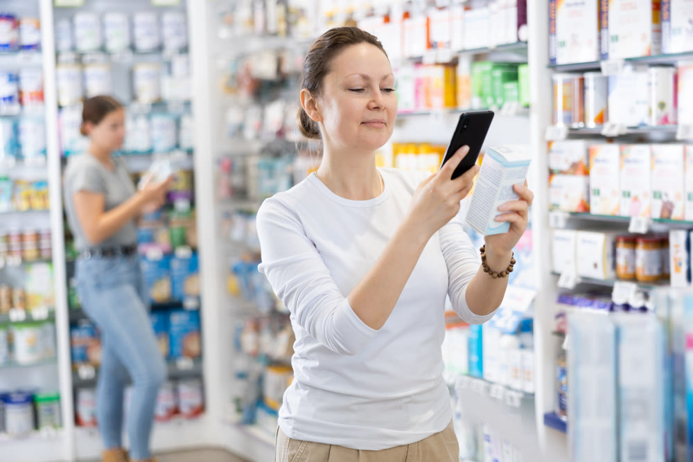 Using smartphone to read information - woman scans a QR code on package of cosmetics