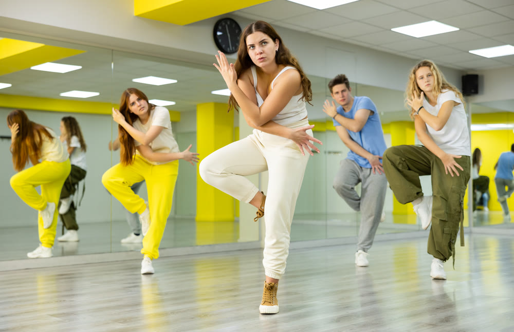 Group of young active tween dancers in casual wear moving with crossed hands during dance training in class