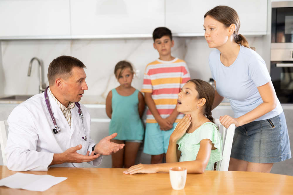 Family physician consults girl child with sore throat from large family at home