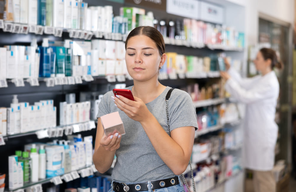 In pharmacy visitor scan QR Code and reads composition of cream for problematic skin.