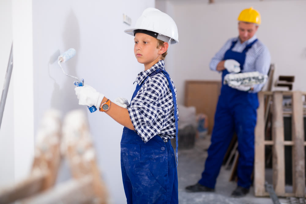 Boy painting wall, renovating home with father