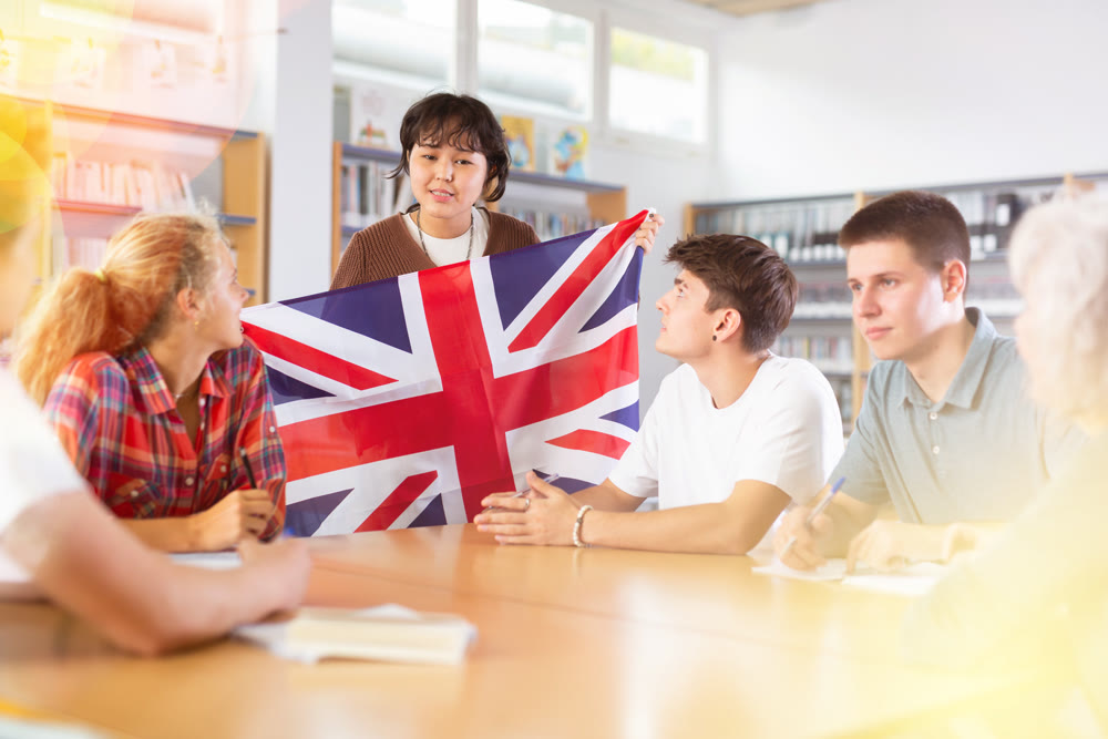 School student girl tells her classmates about the country of Great Britain, holding flag in her hands