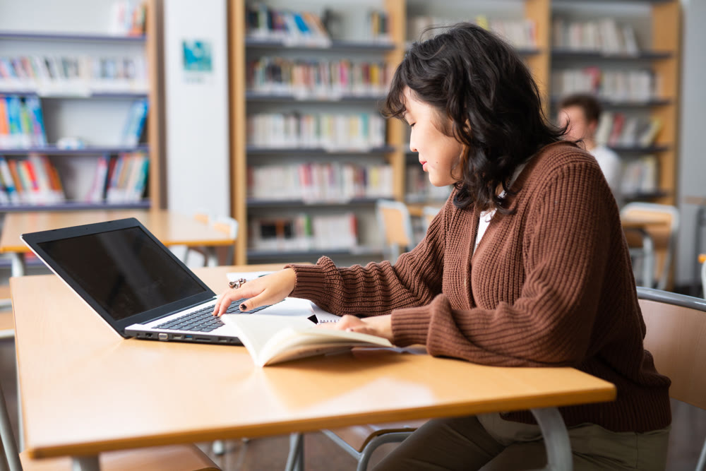 Asian girl with teenagers students studying in school library