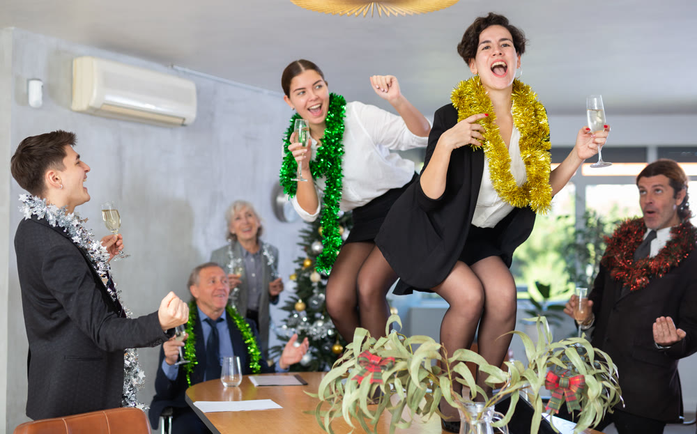 Young women dancing on table during New Year celebration in office