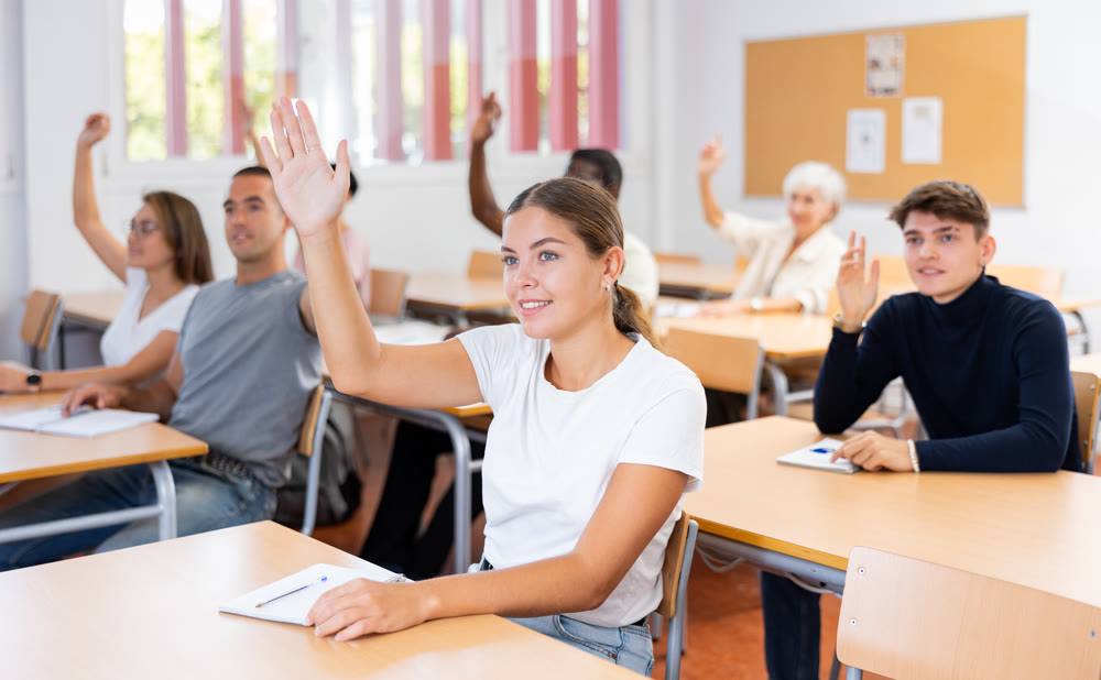 Young woman student raising her hand and smiling