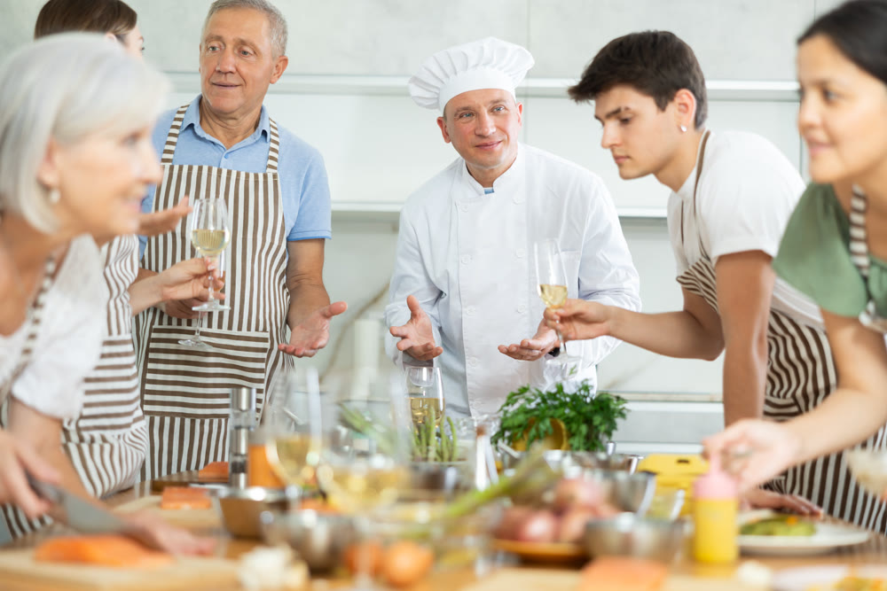 Adult male cook teaches cooking to group of people