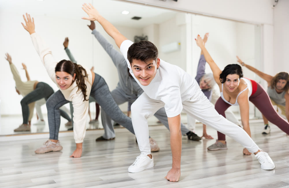 Caucasian guy practising dance moves with other people in dance studio