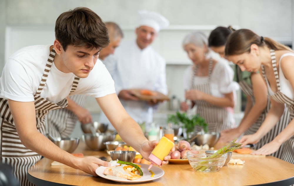 Chef apprentices learn how to cook delicious salmon fillet with asparagus and gravy together in cooking class