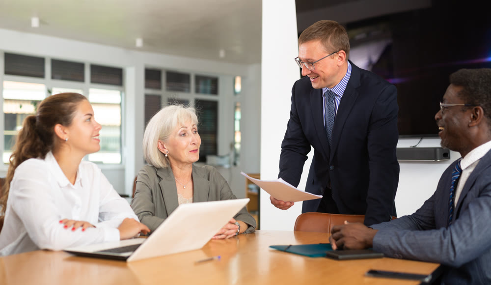 Middle-aged man head of department reports about success and sales growth at meeting.