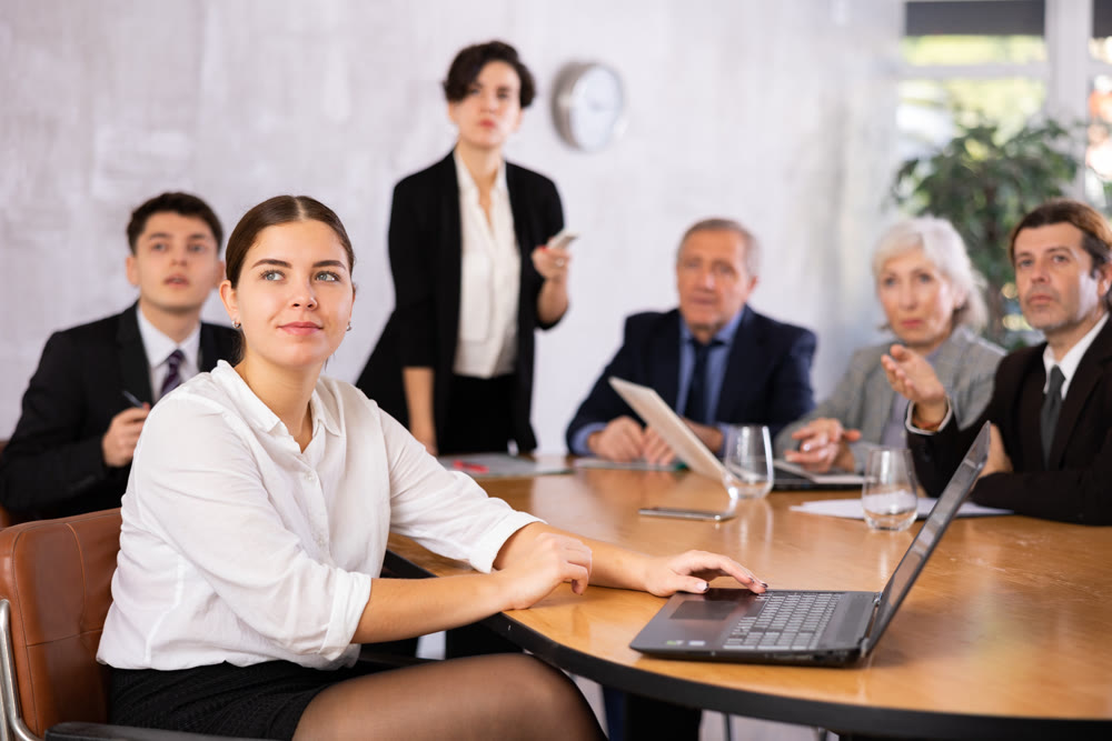 Woman and man sitting at table beside during meeting in conference room