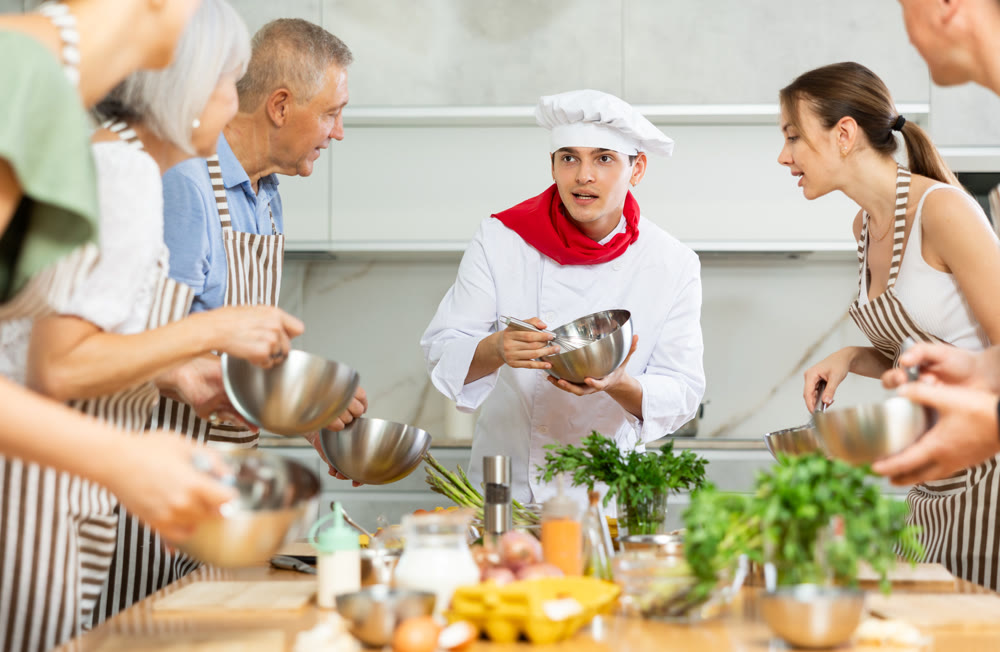 Young guy cook teaches to cook group of people