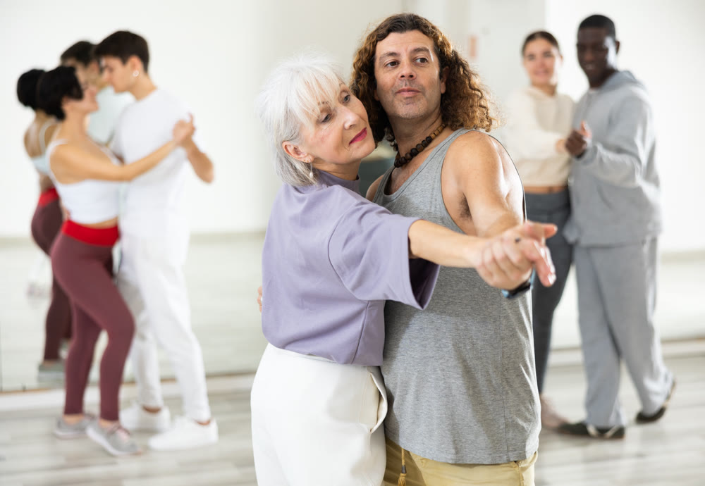 Smiling mature woman and man learning pair dances