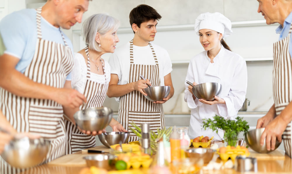 Young female cook teaches to cook group of people