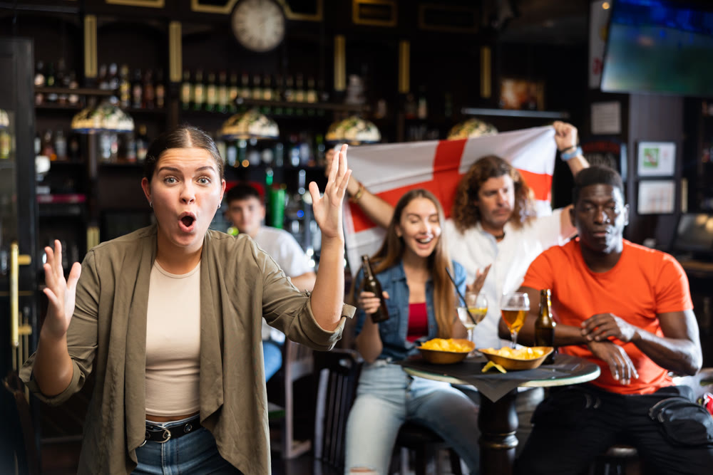 Young girl rejoicing at victory of favorite team of England while watching match in sports bar