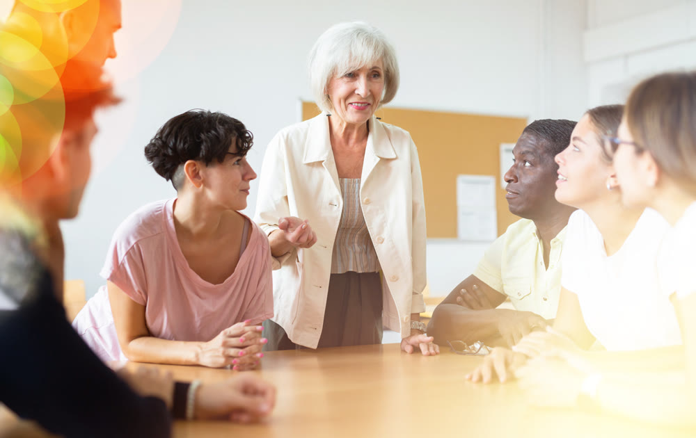 Group of people communicating in Spanish-speaking club with elderly female tutor