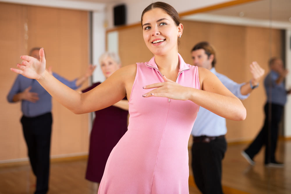 Young woman practicing ballroom dance pose in dance studio