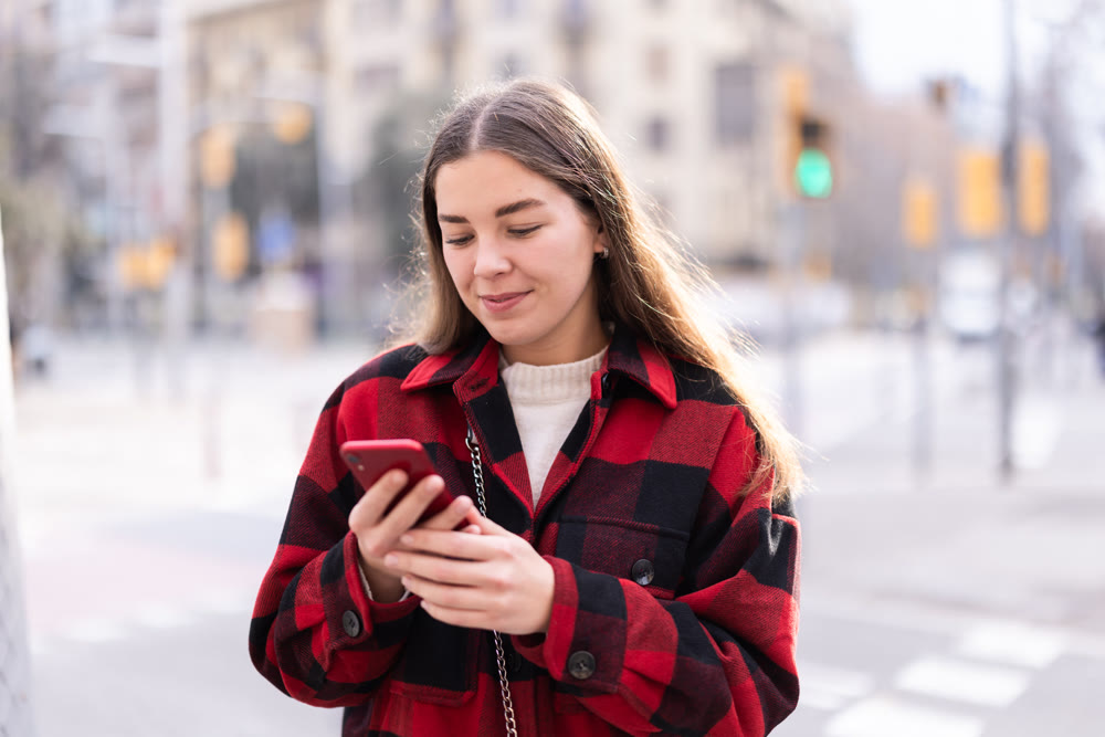 Young woman standing outside and holding phone