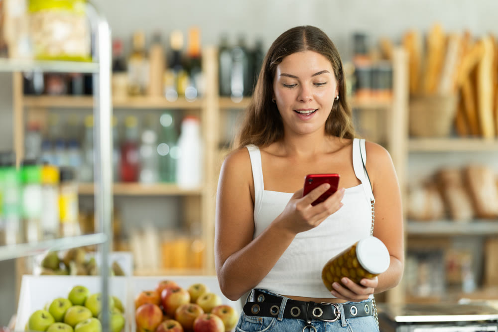 Young woman scanning qr code of olives