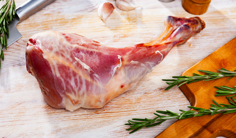 Raw lamb leg with rosemary and garlic. Fresh and raw meat
