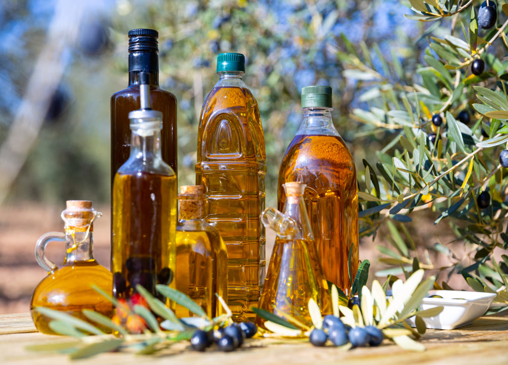 Various kinds of oil on the table on background of olive tree