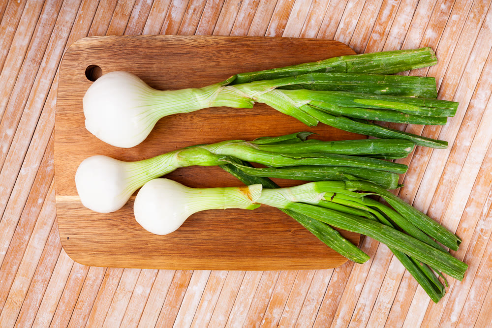 Whole green young onion bulbs on wooden desk