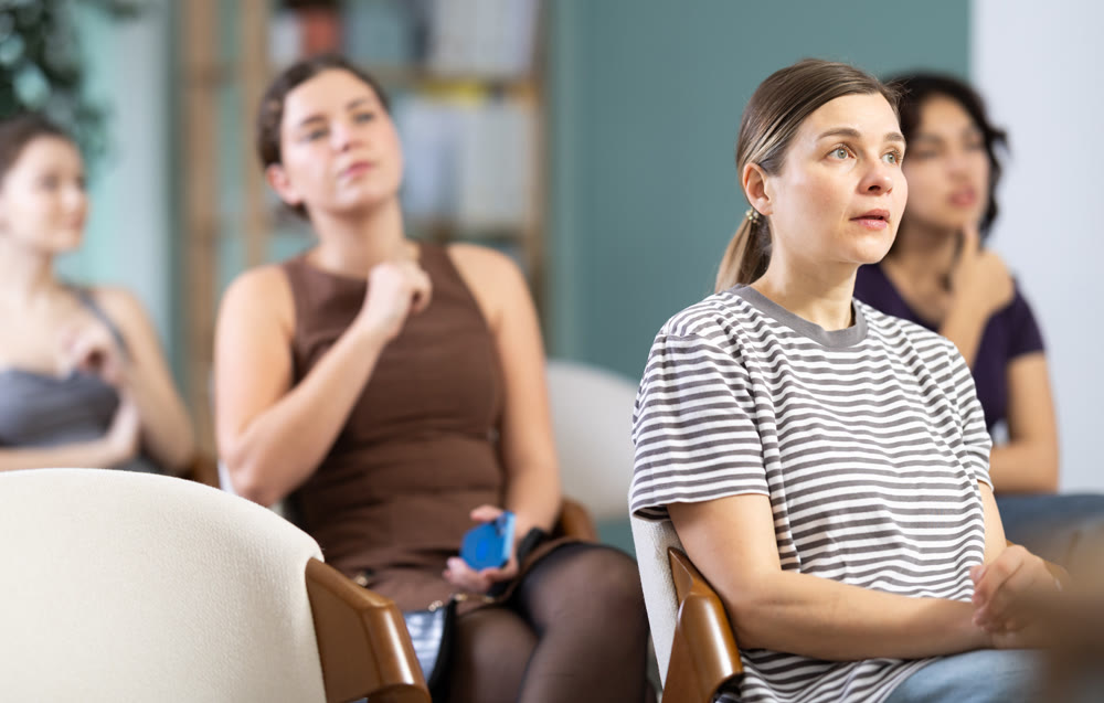 Young girl student dressed in ordinary clothes sitting and listening lecture in university hall